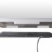 Side view of two stacked flat panels, the top with white edges and the bottom in dark gray, both connected by a cable.