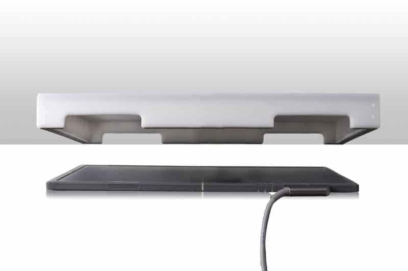 Side view of two stacked flat panels, the top with white edges and the bottom in dark gray, both connected by a cable.