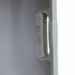 Close-up of a white plastic handle mechanism on the edge of a medical equipment panel.