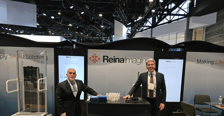 Two men stand beside a large display showcasing various medical equipment in a well-lit environment.